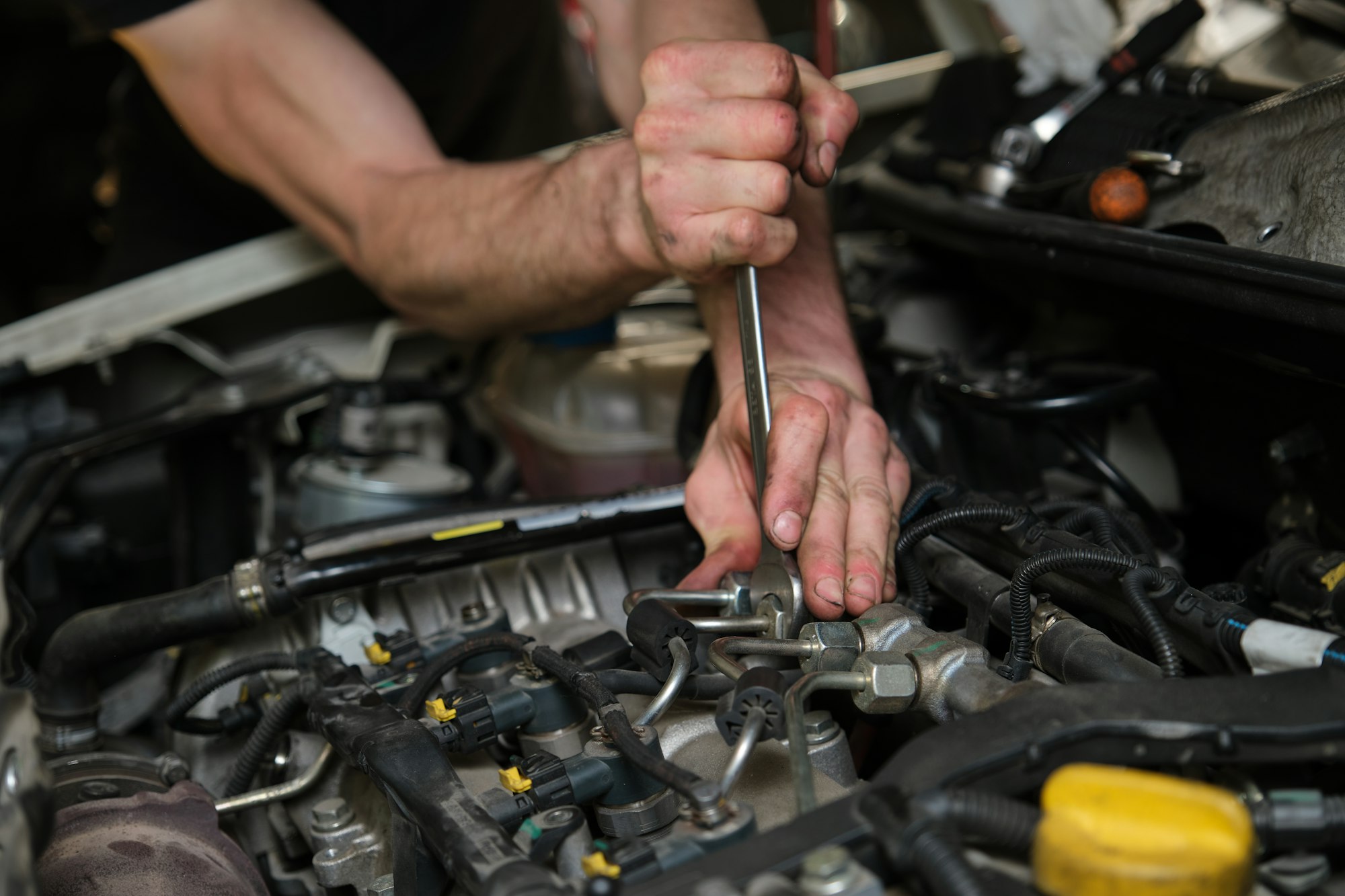 Close up of car mechanic hands removing fuel injectors.