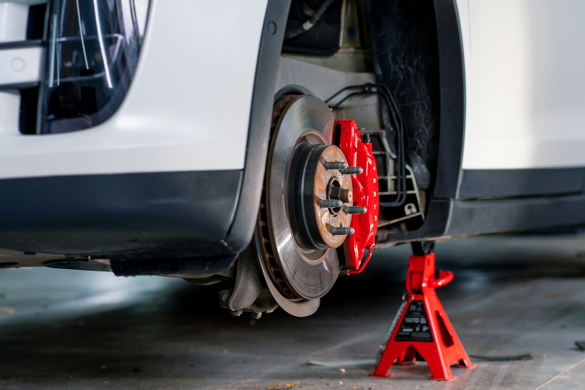 Detailing of the brake disc and bumper of a white luxury car during a car wash at a car service